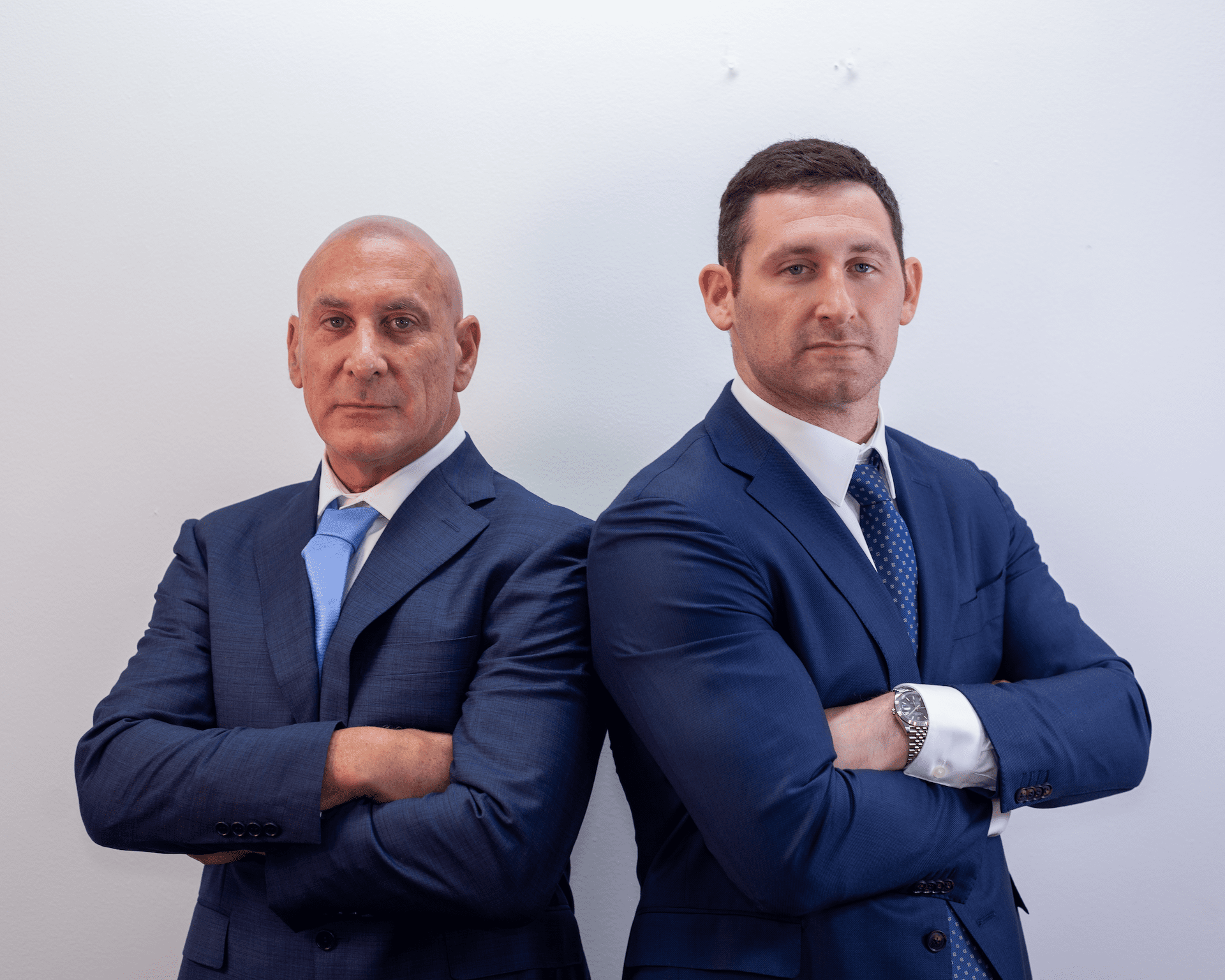 Personal injury attorneys Scott and Alex Senft, back to back, arms crossed.